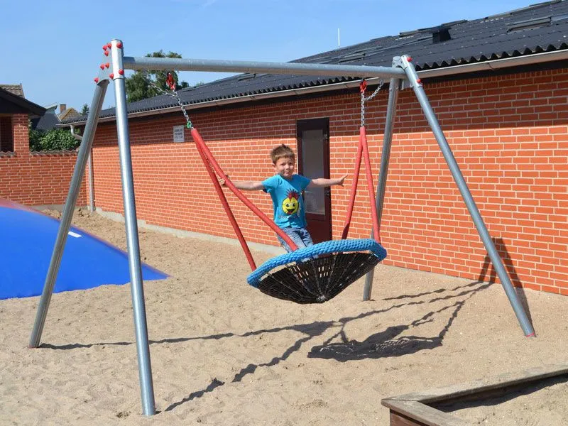 Vogelnestschaukel mit schaukelndem Kind im Kindergarten