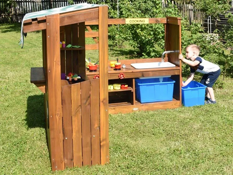 Outdoor children's kiosk with play kitchen side view in the garden Outdoor children's kiosk with play kitchen side view in the garden