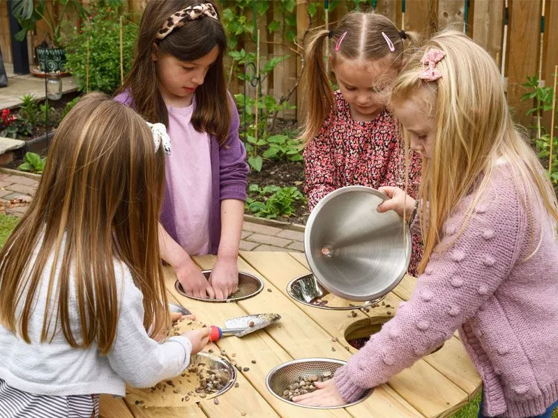 Outdoor round experimental and sand play table with happy children at play Outdoor round experimental and sand play table with happy children at play