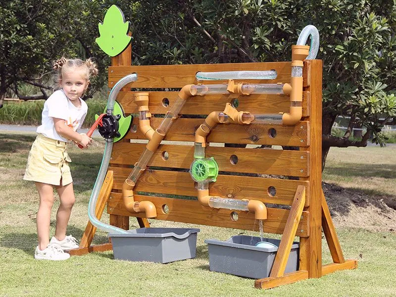 Outdoor Wasserspielwand mit fröhlich spielendem Mädchen auf dem Spielplatz