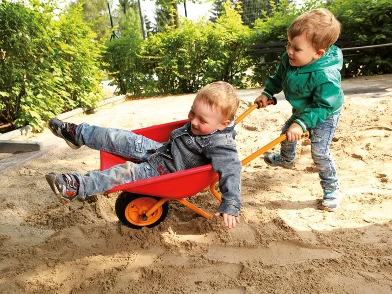 TopPlay Schubkarre mit lustigen Kindern beim Spaß haben im Sandkasten